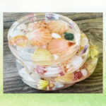 Four coasters made out of plastic and seashells.